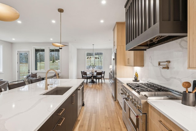 kitchen featuring extractor fan, light stone counters, light brown cabinets, high quality appliances, and pendant lighting