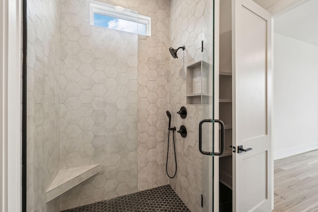 bathroom with wood-type flooring and a tile shower