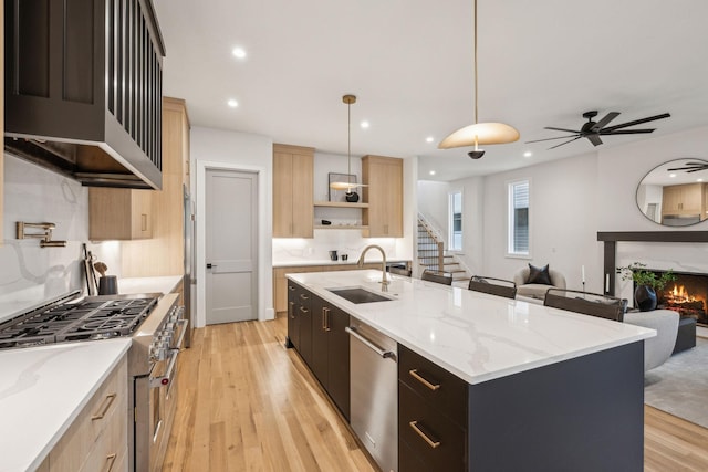 kitchen featuring sink, decorative light fixtures, light brown cabinets, an island with sink, and stainless steel appliances