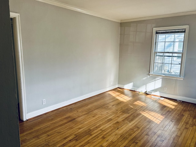 spare room with baseboards, crown molding, and wood finished floors