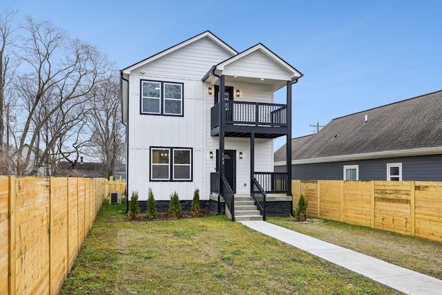 view of front of home with central AC, a front yard, and a balcony