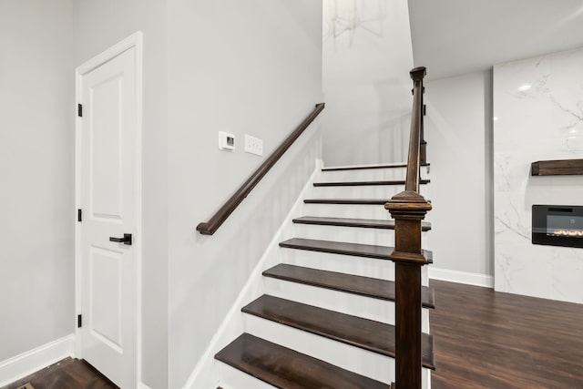 stairs with wood-type flooring and a premium fireplace