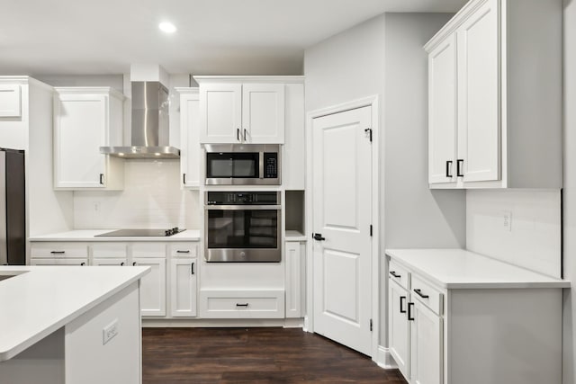 kitchen with tasteful backsplash, white cabinets, stainless steel appliances, dark wood-type flooring, and wall chimney exhaust hood