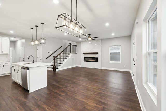 kitchen featuring sink, hanging light fixtures, white cabinets, a center island with sink, and stainless steel dishwasher