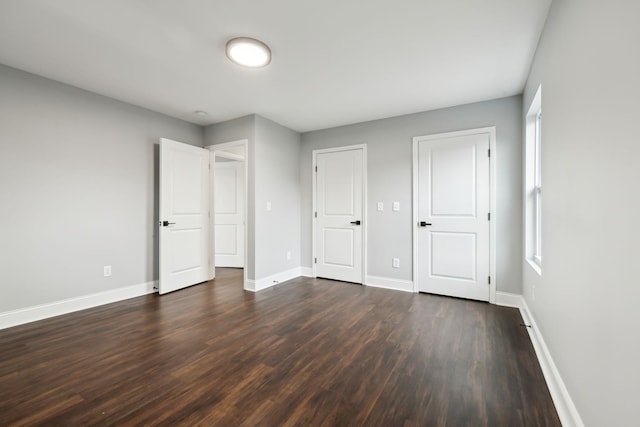 unfurnished bedroom featuring multiple windows and dark hardwood / wood-style floors