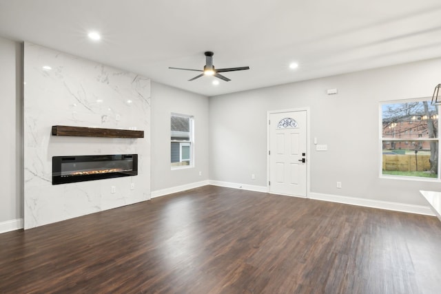 unfurnished living room with ceiling fan, a fireplace, and dark hardwood / wood-style flooring