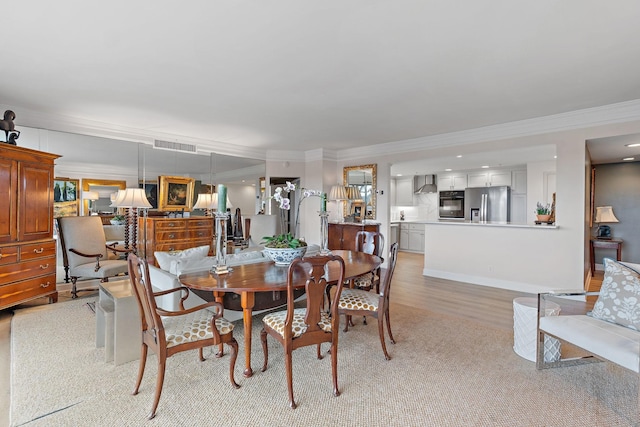 dining area with ornamental molding and light hardwood / wood-style flooring