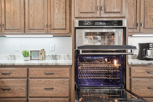 kitchen featuring light stone counters and double oven