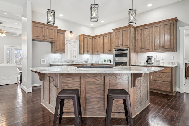 kitchen featuring light stone counters, stainless steel appliances, decorative light fixtures, and a kitchen island