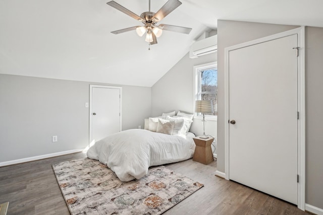 bedroom with ceiling fan, wood-type flooring, a wall mounted AC, and vaulted ceiling