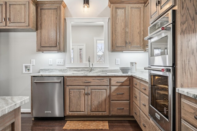 kitchen featuring sink, dark wood-type flooring, light stone countertops, and appliances with stainless steel finishes