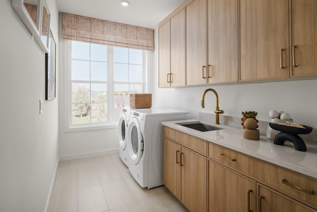 laundry area featuring cabinets, washer and clothes dryer, and sink