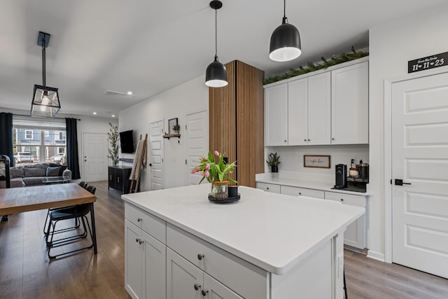 kitchen featuring a kitchen island, light wood-type flooring, hanging light fixtures, and white cabinets