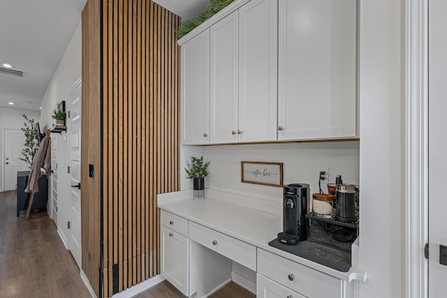 interior space featuring hardwood / wood-style flooring, built in desk, and white cabinets