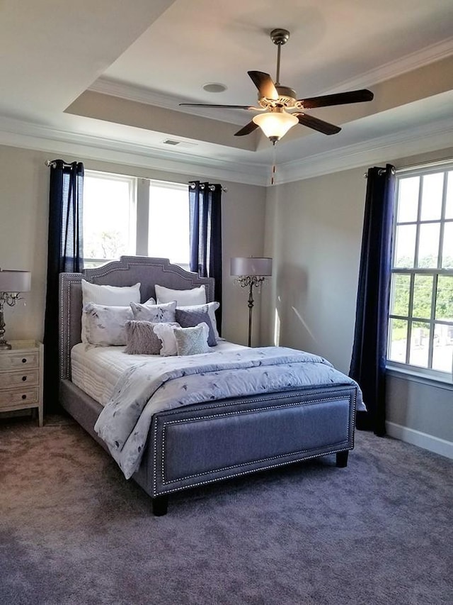 bedroom featuring dark carpet, ornamental molding, a raised ceiling, and ceiling fan