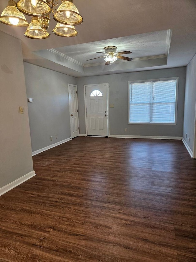 foyer featuring a tray ceiling, dark wood-type flooring, ornamental molding, and ceiling fan with notable chandelier