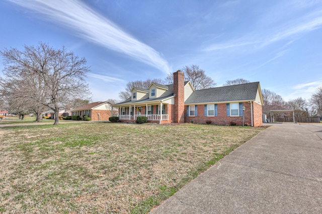 view of front of property with a porch, a chimney, brick siding, and a front lawn