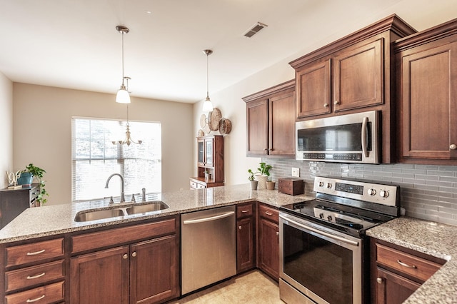 kitchen with kitchen peninsula, pendant lighting, stainless steel appliances, and sink