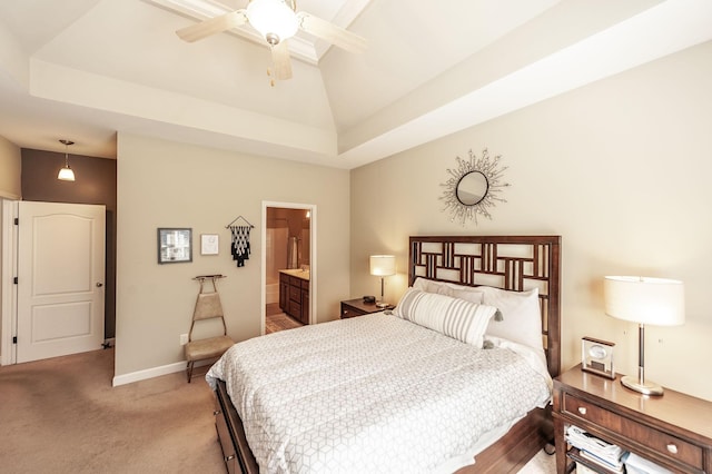 bedroom with a raised ceiling, light carpet, connected bathroom, and lofted ceiling