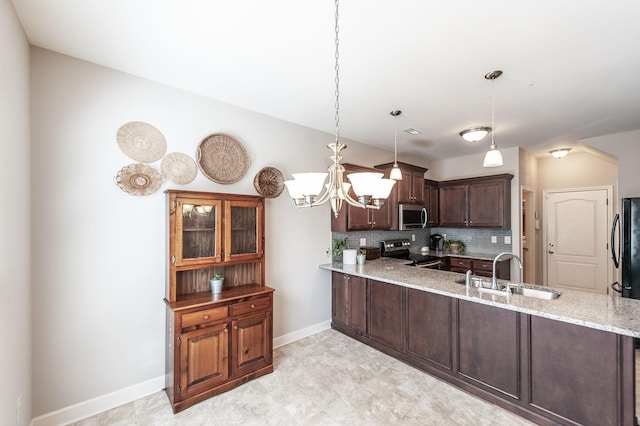 kitchen featuring sink, light stone counters, decorative light fixtures, stainless steel appliances, and kitchen peninsula