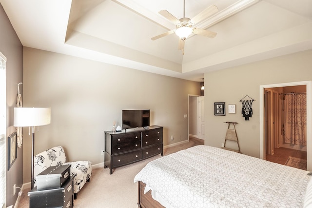 bedroom with light colored carpet, ceiling fan, and a raised ceiling