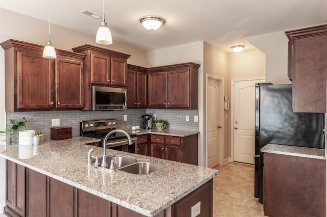 kitchen with hanging light fixtures, stainless steel appliances, light stone countertops, sink, and kitchen peninsula