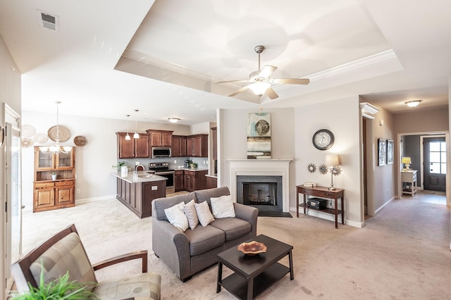 living room with light colored carpet, sink, ceiling fan, a raised ceiling, and crown molding