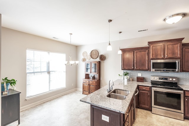 kitchen with appliances with stainless steel finishes, sink, pendant lighting, and backsplash