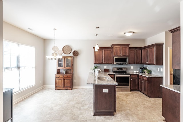 kitchen featuring appliances with stainless steel finishes, sink, decorative light fixtures, dark brown cabinets, and tasteful backsplash