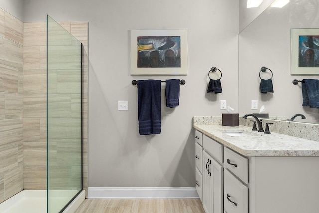 bathroom with vanity, wood-type flooring, and a tile shower