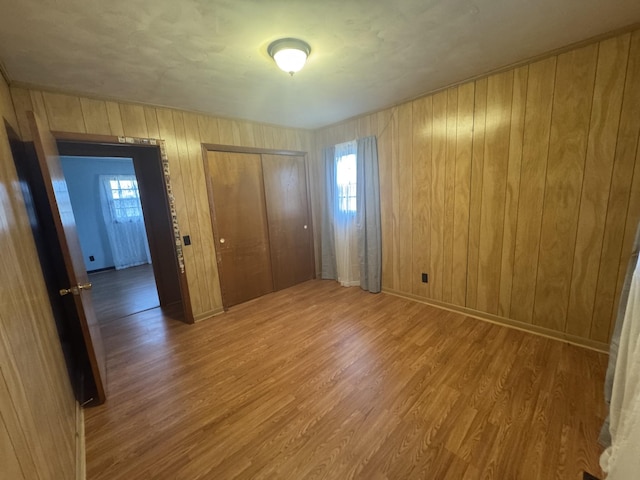 unfurnished bedroom featuring hardwood / wood-style floors, wood walls, and a closet