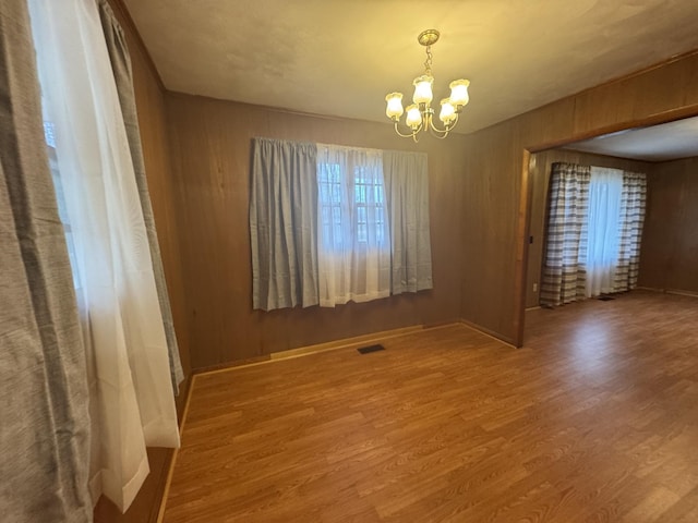 spare room featuring an inviting chandelier and hardwood / wood-style flooring