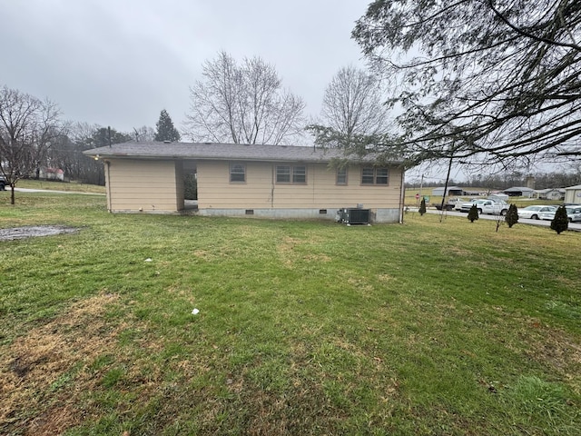 rear view of house featuring central AC and a lawn