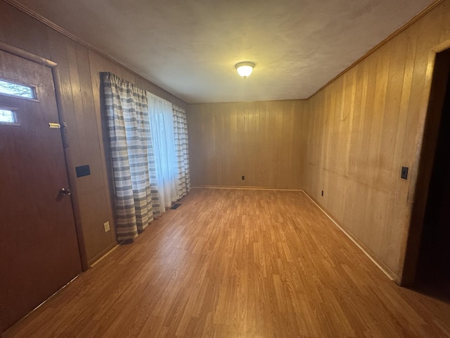 interior space featuring crown molding, light hardwood / wood-style flooring, and wood walls