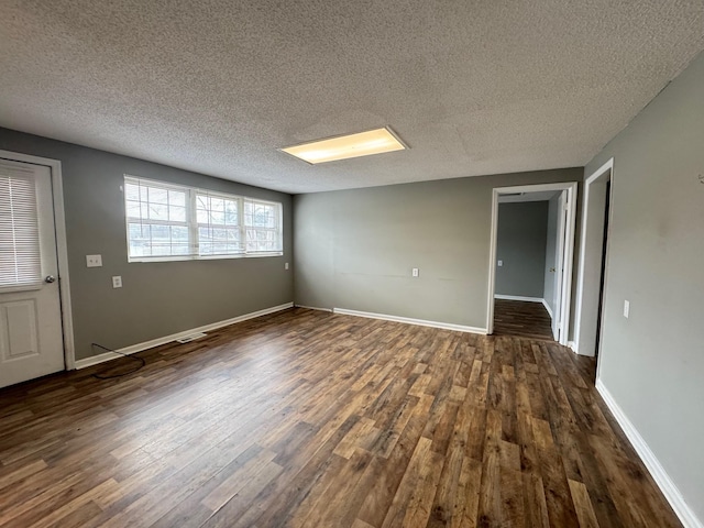 unfurnished room featuring dark wood-type flooring and a textured ceiling