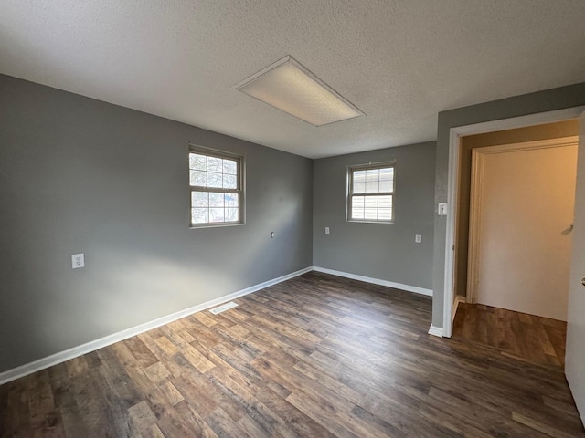 empty room with a textured ceiling and dark hardwood / wood-style flooring