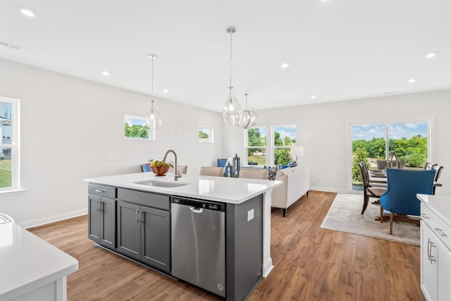 kitchen featuring sink, stainless steel dishwasher, gray cabinets, an island with sink, and pendant lighting