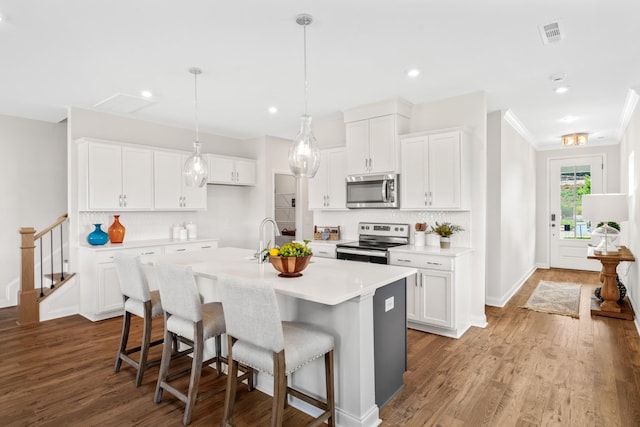 kitchen with stainless steel appliances, an island with sink, white cabinets, and light hardwood / wood-style floors