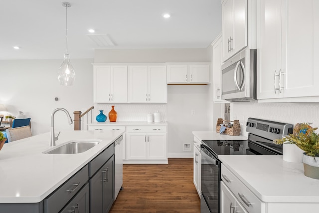 kitchen featuring decorative light fixtures, white cabinetry, an island with sink, sink, and stainless steel appliances