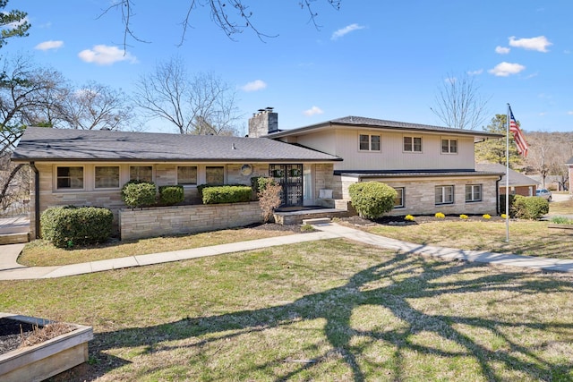 split level home featuring stone siding, a chimney, and a front lawn