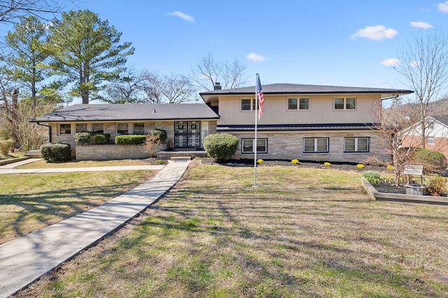 split level home featuring stone siding and a front yard