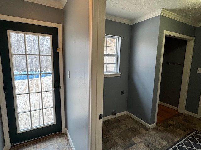 doorway to outside with baseboards, a textured ceiling, ornamental molding, and stone finish floor