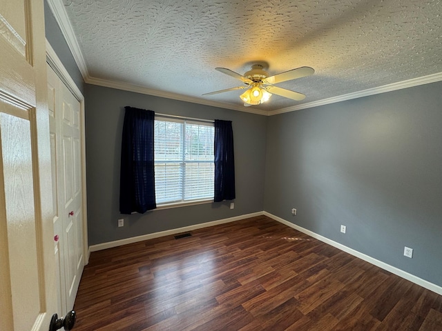 unfurnished room with dark wood finished floors, a textured ceiling, crown molding, and baseboards