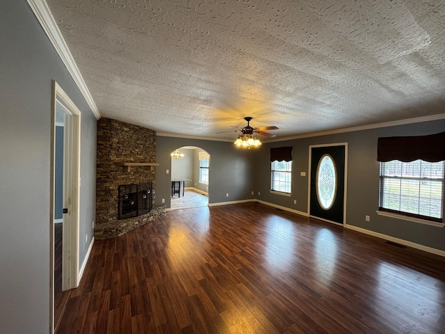 unfurnished living room featuring visible vents, ornamental molding, a stone fireplace, wood finished floors, and arched walkways