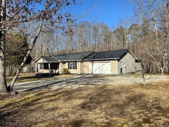 ranch-style home with metal roof, an attached garage, and dirt driveway