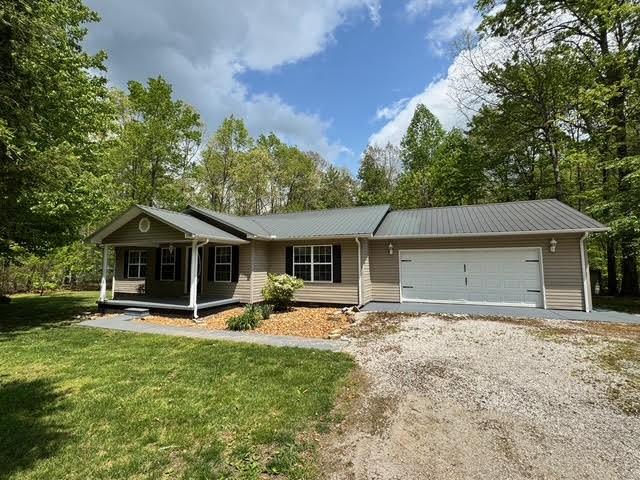 238 Laurens Ln, Grimsley, TN 38565 - ranch-style home featuring covered porch, a front yard, dirt driveway, metal roof, and an attached garage
