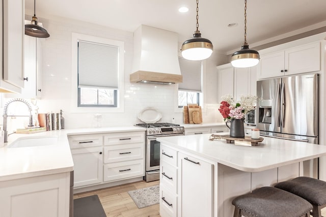 kitchen featuring sink, stainless steel appliances, custom range hood, white cabinets, and a kitchen island