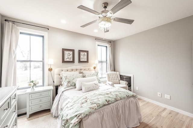 bedroom with ceiling fan, light hardwood / wood-style floors, and multiple windows