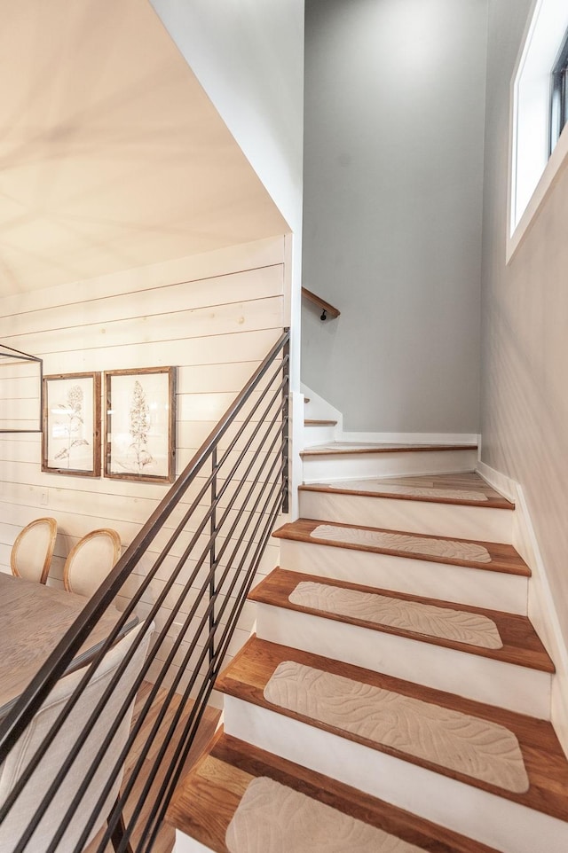 staircase with wood-type flooring and wood walls