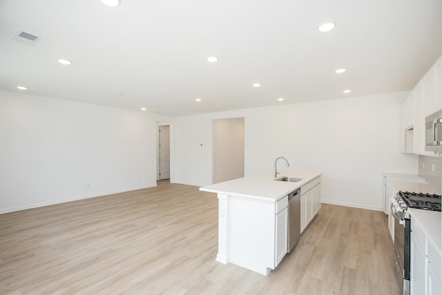 kitchen with sink, a center island with sink, light wood-type flooring, stainless steel appliances, and white cabinets